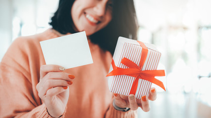 Woman holding white blank card and gift box.