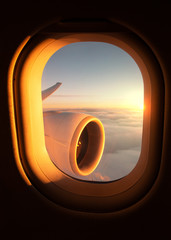 View out of an airplane window of the jet's wing and engine with a stunning sunset