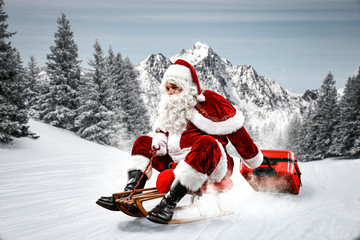 Wall Mural - Red Santa Claus riding a wooden sled. An older man with a beard delivers presents to a child. Winter mountains landscape and snow-covered trees with frost. Fir branches, winter time. Christmas spells