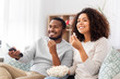 © Syda Productions - people and leisure concept - african american couple with popcorn watching tv at home