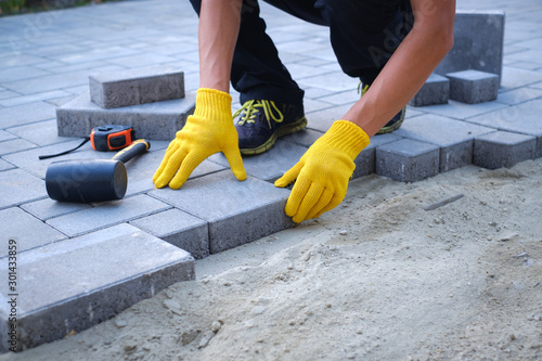 Fotografía The master in yellow gloves lays paving stones in layers
