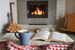 © Ivan Kmit - Hygge concept with open book and cup of tea near burning fireplace