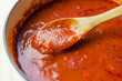 Wooden spoon stirring a pot of marinara sauce. Close up view. 