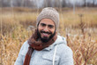 © Anne Richard - Closeup of cute smiling young bearded mixed race man in warm clothes and beanie hat standing outdoors in a field during a grey afternoon, Quebec City, Quebec, Canada