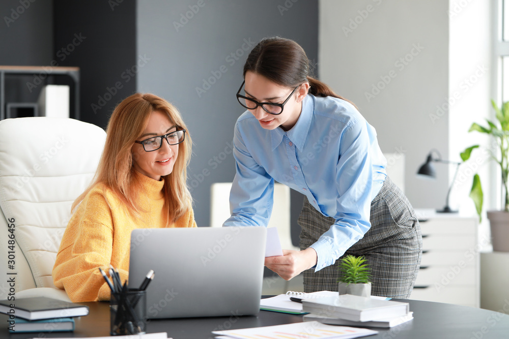 Mature businesswoman and her assistant working in office - obrazy, fototapety, plakaty 