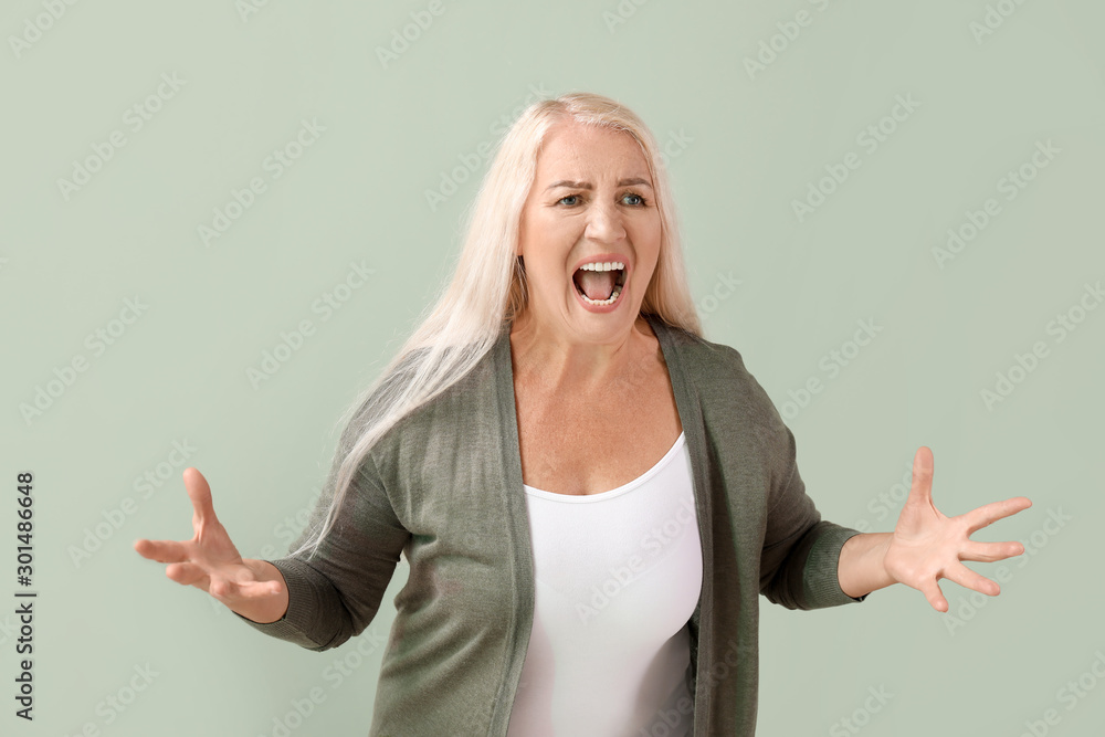 Angry mature woman on color background