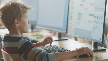 Elementary School Computer Science Classroom: Smart Little Schoolboy Works on Personal Computers, Learning Programming Language for Software Coding. Schoolchildren Getting Modern Education