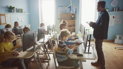 Elementary School Computer Science Classroom: Teacher Uses Tablet Computer, Explains Lesson to Diverse Group of Smart Children. Informatics Class Kids Learn: Internet Safety, Software Programming
