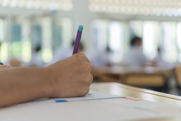 Wall Mural - school or university students hands taking exams, writing examination room with holding pencil on op