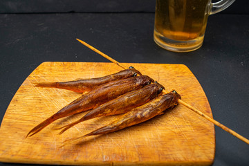 Dried mullet on a wooden Board with a mug of beer on the table. Fish and seafood cuisine. Tasty snack.