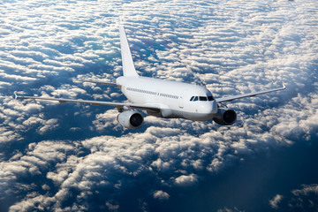 White passenger plane flies high over the clouds.