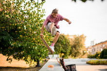 Boy Jumping With The Balance Board In Hand On The Concrete Border In The Park