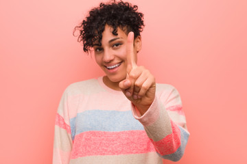 Wall Mural - Young mixed african american teenager woman showing number one with finger.