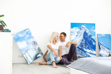 Wall Mural - young couple hangs a large photo canvas at home