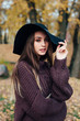 © Elena Kratovich - Outdoor fashion photo of young beautiful woman in black hat in autumn park