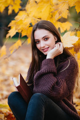 Beautiful girl in autumn forest reading a book