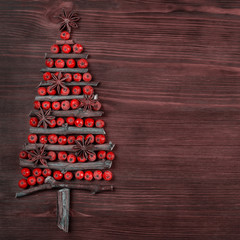 Christmas tree made of wooden branches and rowan berries. New Year celebration concept with Christmas tree with star and red bauble decorations over wood background. Place for text, Flat lay, top view