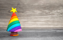 Playful Christmas Concept. Handmade Miniature Christmas Tree In Rainbow Colors. Soft Wood Background. Plenty Of Free Space To Write Text. 