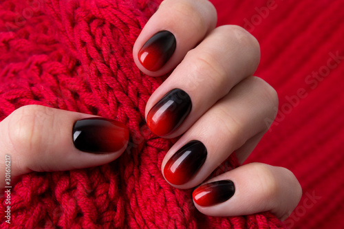Female hand with red black ombre gradient nails hold wool textile fabric Lerretsbilde