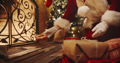 authentic santa clause leaving christmas gifts near fireplace and christmas tree - chritmas spirit, 