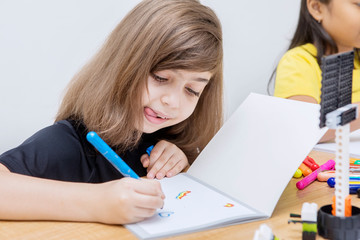Wall Mural - Caucasian little girl drawing with crayon in the class