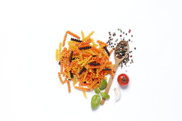 Flat lay composition of colored pasta, cherry tomatoes, spices, basil, olive oil, garlic isolated on a white background.