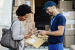 © Drazen - Happy African American woman signing on digital tablet for a package delivery.