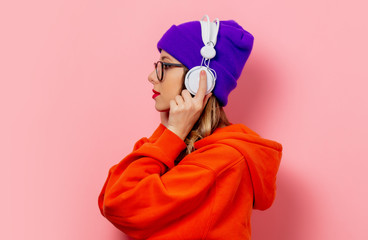 Poster - Style girl in orange hoodie and purple hat with headphones on pink background