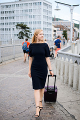 Front view of a traveler woman walking carrying a suitcase in a city railway station. Young business woman is going to have a business trip to some other city