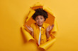 © wayhome.studio  - Uncertain cute woman with Afro hairstyle spreads palms, has confused clueless expression makes decision, shrugs shoulders has no idea poses in yellow paper hole background. How change life for better?