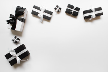 Many birthday holiday gift presents wrapped in black and white paper with black and white satin ribbon bows on white background. Photo with copy blank space.