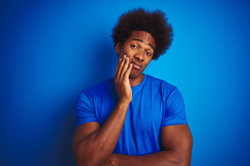 Sticker - African american man with afro hair wearing t-shirt standing over isolated blue background thinking looking tired and bored with depression problems with crossed arms.