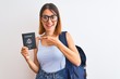 © Krakenimages.com - Beautiful redhead student woman wearing backpack and holding passport of united states very happy pointing with hand and finger