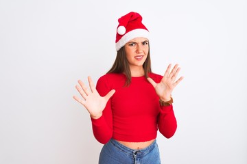 Young beautiful girl wearing Christmas Santa hat standing over isolated white background afraid and terrified with fear expression stop gesture with hands, shouting in shock. Panic concept.