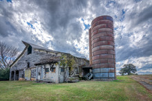 Old Abandoned Barn With Silo Under Storm Clouds