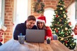 © Krakenimages.com - Young beautiful couple smiling happy and confident. Sitting on desk using laptop around christmas tree at home
