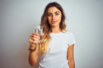 Canvas Print - Young beautiful woman drinking a glass of water over white isolated background with a confident expression on smart face thinking serious