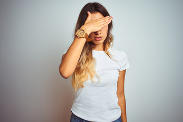 Canvas Print - Young beautiful woman wearing casual white t-shirt over isolated background covering eyes with hand, looking serious and sad. Sightless, hiding and rejection concept