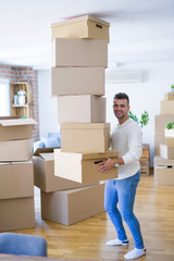 Poster - Young handsome man moving to a new apartment, holding a pile of cardboard boxes, happy for new home