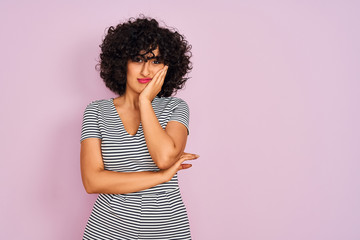 Canvas Print - Young arab woman with curly hair wearing striped dress over isolated pink background thinking looking tired and bored with depression problems with crossed arms.