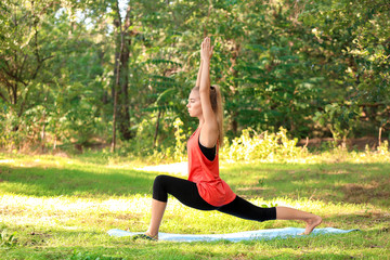 Wall Mural - Beautiful young woman practicing yoga in park