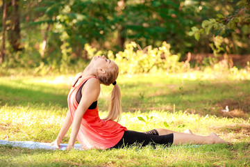 Wall Mural - Beautiful young woman practicing yoga in park