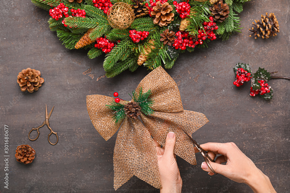 Woman making beautiful Christmas wreath at table