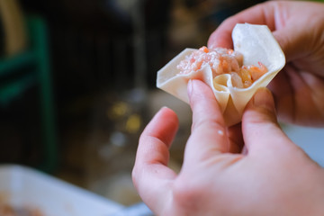 Close up and selective focus of hands cooking homemade making of Traditional chinese food dumpling called Shumai in Thailand called kanom jeep. Cooking by steam in bamboo basket.