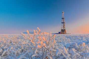 Wall Mural - In a winter snow-covered tundra, a well is being drilled at an oil and gas field. Polar day. Beautiful sky. The drilling rig is covered in snow.