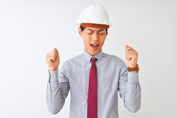 Wall Mural - Chinese architect man wearing tie and helmet standing over isolated white background excited for success with arms raised and eyes closed celebrating victory smiling. Winner concept.