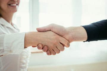 Shaking hands, concept for teamwork: Close up of man and woman shaking hands in the office