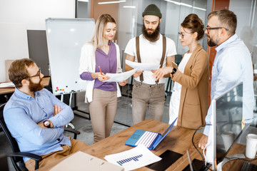 Wall Mural - group of diverse colleagues meeting in the office, creative bearded hipster telling emotionally a ne