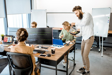 Wall Mural - office workers eating salad while sitting on the working place during a lunch time without leaving t
