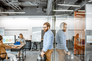 Wall Mural - people working in the office, young man walks into the office with a safety helmet upon arriving at 